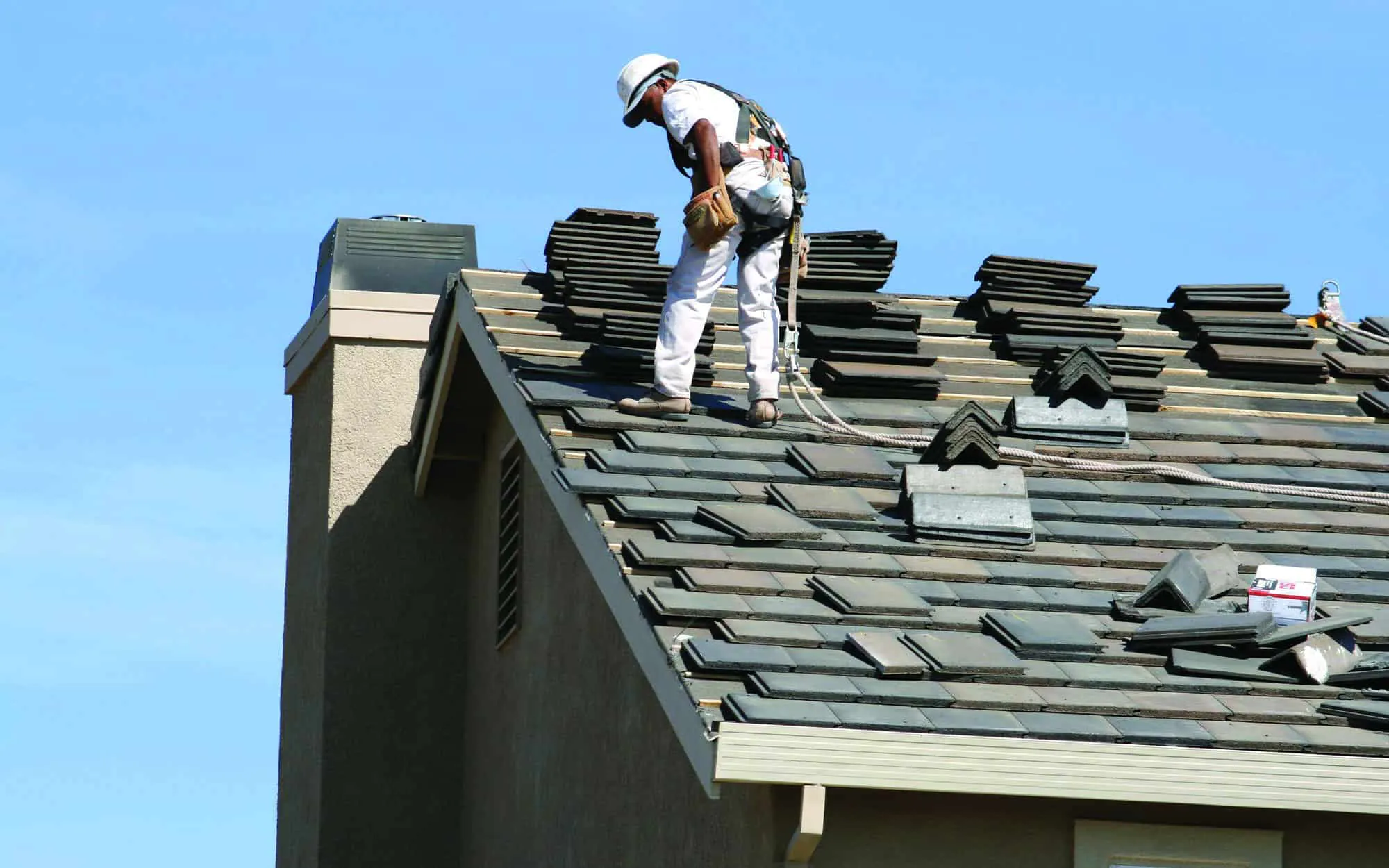 Roofer-talking-to-coworkers-while-standing-on-shingle-roof